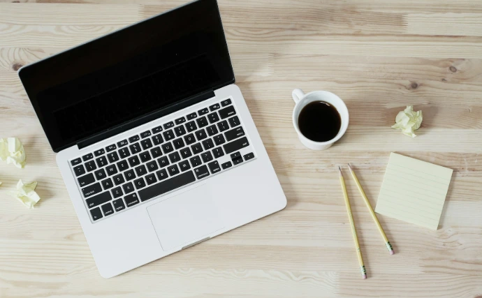 turned off MacBook Pro beside white ceramic mug filled with coffee